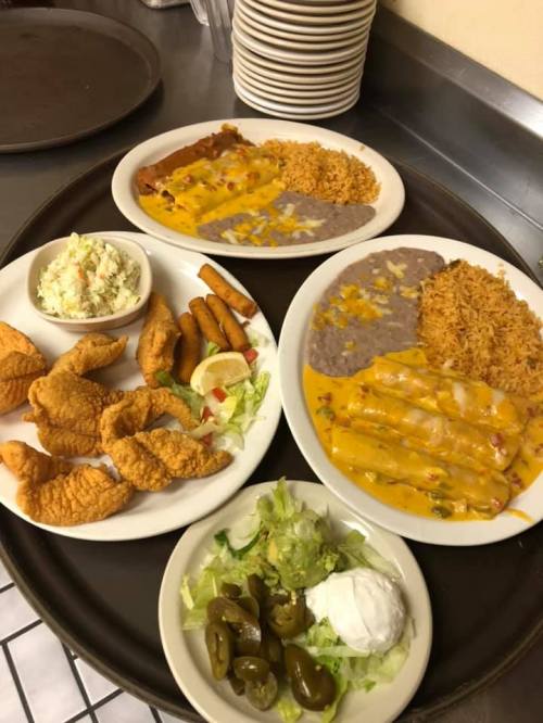A tray with two plates of Mexican food, including enchiladas, rice, beans, fried fish, and a side salad.