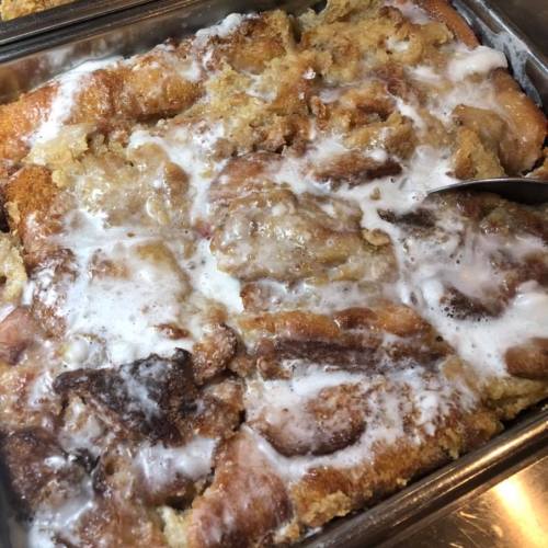 A close-up of a baked dessert with a golden-brown crust and a creamy, frosted top.