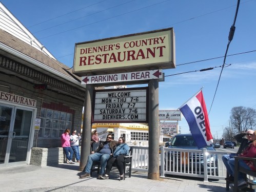 A restaurant sign reads "Dienner's Country Restaurant" with hours and an "Open" flag; people sit outside.