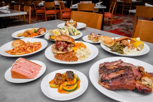 A variety of dishes including meats, sides, and desserts arranged on a table in a restaurant setting.