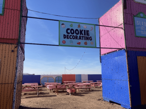 Colorful entrance to a cookie decorating area with picnic tables and a clear blue sky in the background.