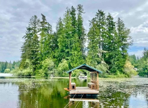 A serene lake scene featuring a small dock surrounded by lush green trees under a cloudy sky.