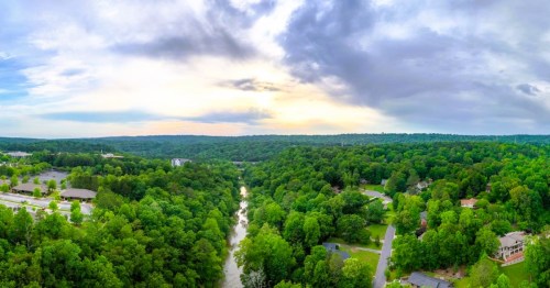 Aerial views of the Cahaba River flowing through Vestavia Hills, a wealthy town in Alabama, surrounded by homes nestled in dense forest.