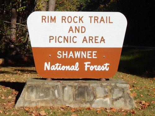 Sign for Rim Rock Trail and Picnic Area in Shawnee National Forest, featuring brown and white colors.