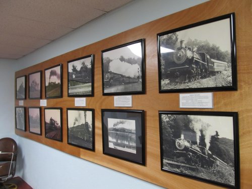 A wall display featuring framed black-and-white photographs of vintage steam trains and railway scenes.