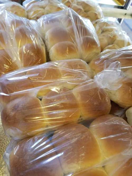 A close-up of freshly baked bread rolls packaged in clear plastic bags.