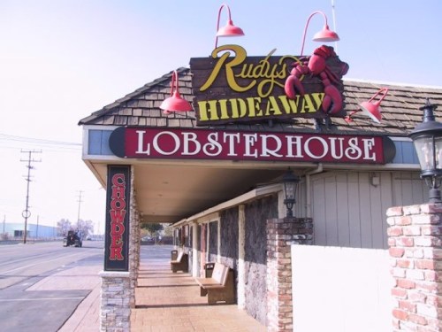 Sign for Rudy's Hideaway Lobsterhouse, featuring a lobster graphic and outdoor seating area.