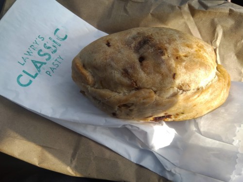 A freshly baked pastry resting on a paper wrapper, showcasing a golden-brown crust with a flaky texture.