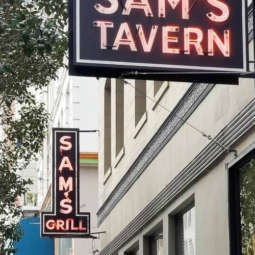 Neon signs for "Sam's Tavern" and "Sam's Grill" on a building exterior.