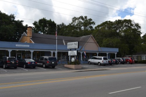 A building labeled "Antique Mill" with parked cars in front, set against a cloudy sky.