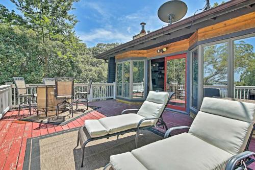 A sunny deck with lounge chairs, a dining table, and trees in the background, featuring a clear blue sky.