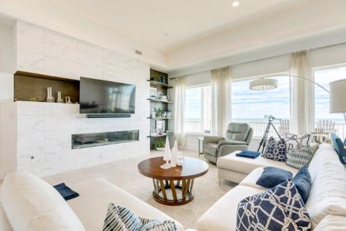 Modern living room with a large TV, cozy seating, and large windows offering a view of the outdoors.