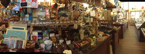 A vibrant store interior filled with various items, including gifts, toys, and home goods, displayed on wooden counters.