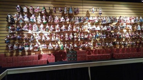 A wall display filled with colorful decorative dolls, arranged in rows above red gift boxes.