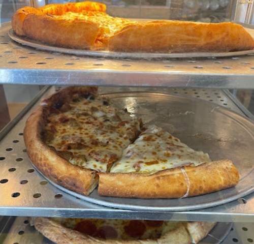 Two pizza slices on a metal rack, one with cheese and the other with pepperoni, both with golden crusts.
