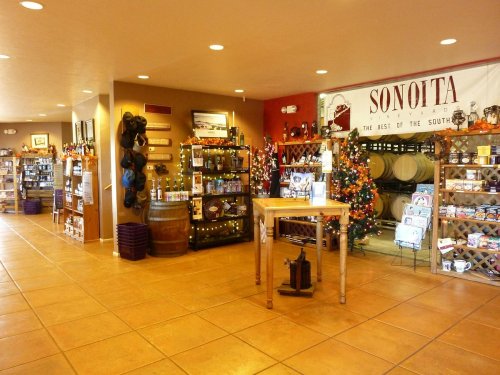 Interior of a shop featuring shelves of products, decorative lights, and a sign for Sonoita, with a warm, inviting atmosphere.