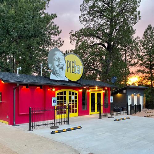 Colorful exterior of a pie shop with a large sign and a cartoonish face, surrounded by trees at sunset.