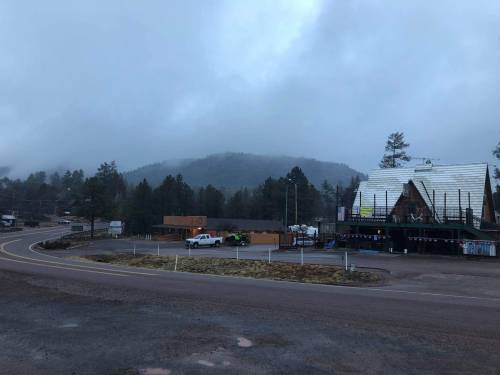 A foggy landscape featuring a small store, mountains in the background, and a winding road.
