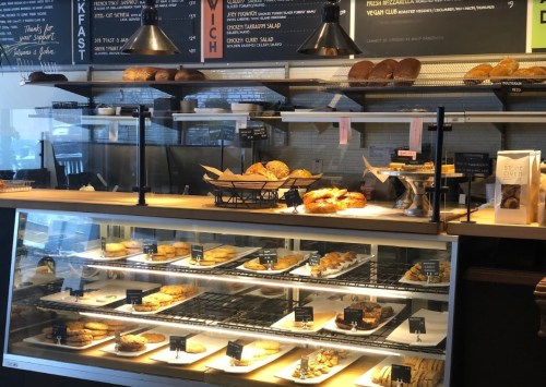 A display case filled with various baked goods, including pastries and bread, in a café setting.