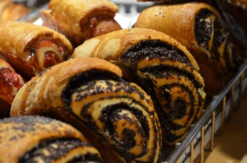 A close-up of freshly baked poppy seed rolls with a swirled pattern, displayed in a metal basket.