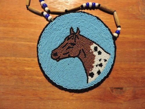 Beaded necklace featuring a circular pendant with a horse's head design on a blue background.