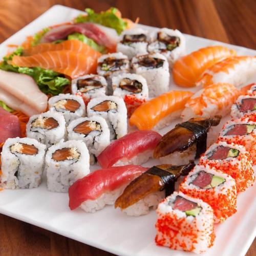 A platter of assorted sushi, including nigiri, sashimi, and rolls, beautifully arranged on a white plate.