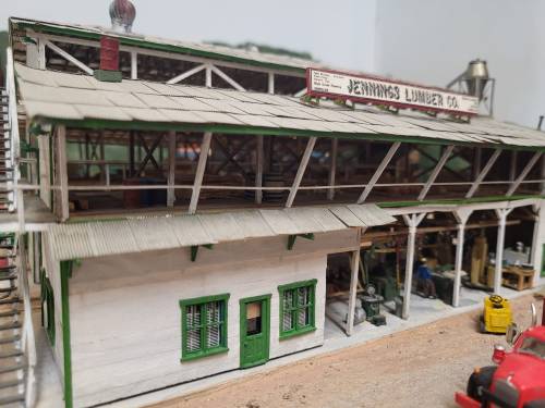 A detailed model of a lumber company building with green accents and a sign reading "Jennings Lumber Co."