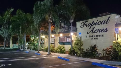 Exterior of Tropical Acres Steakhouse at night, featuring palm trees and a sign with the establishment's name and founding year.
