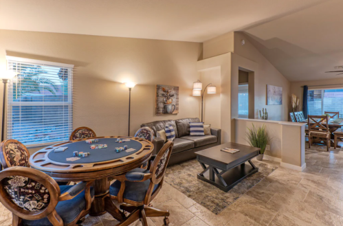 Cozy living space featuring a poker table, sofa, and dining area with warm lighting and neutral decor.