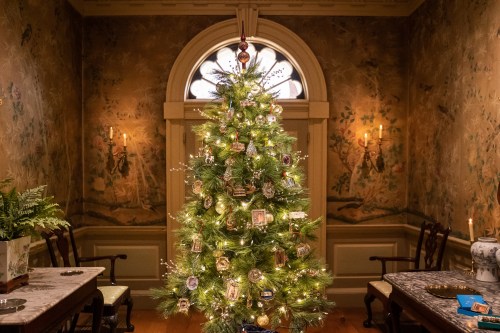 A beautifully decorated Christmas tree with ornaments, surrounded by a cozy room with vintage wallpaper and soft lighting.