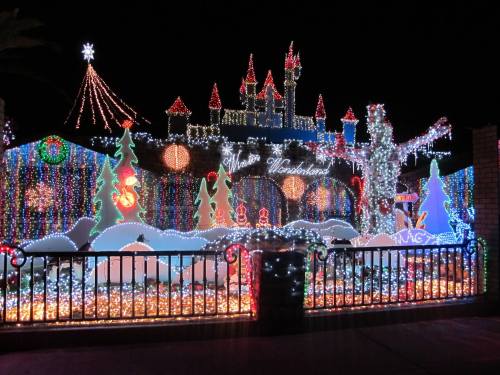 A colorful display of holiday lights featuring a castle, trees, and festive decorations against a night sky.