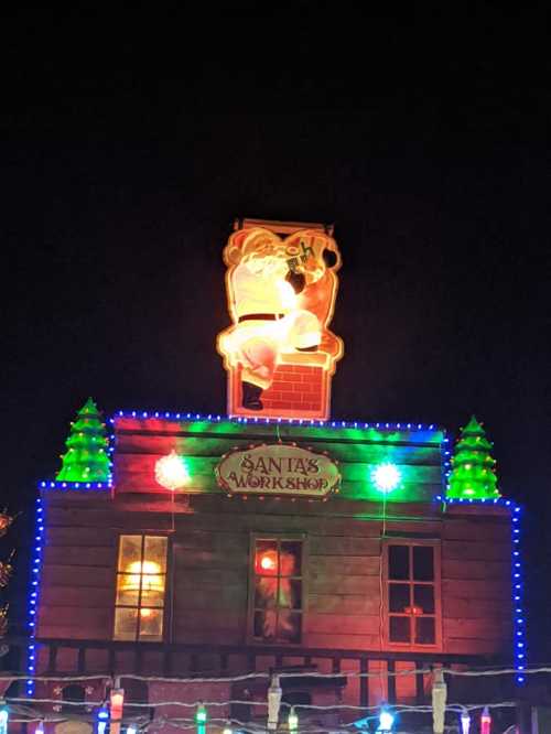 A festive display of Santa's Workshop, illuminated with colorful lights and a glowing Santa figure on the roof.