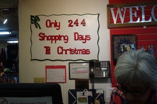 Sign on a wall reads "Only 244 Shopping Days 'Til Christmas," with festive decorations. A person is partially visible below.