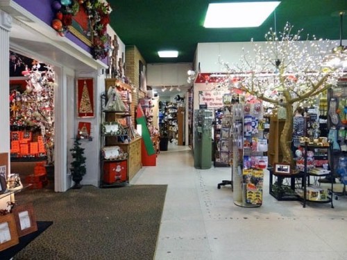A colorful store interior filled with holiday decorations, gifts, and displays, featuring a tree with lights.