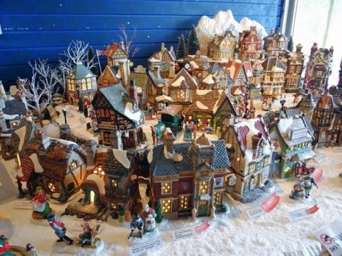 A festive miniature village scene with snow-covered buildings, trees, and figurines, creating a charming holiday atmosphere.