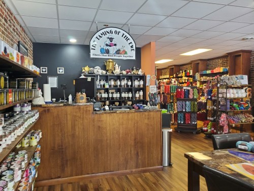 A cozy craft store interior with shelves of yarn, craft supplies, and a welcoming checkout counter.