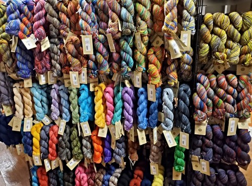 A colorful display of various yarn skeins arranged neatly on a rack, each with a tag.