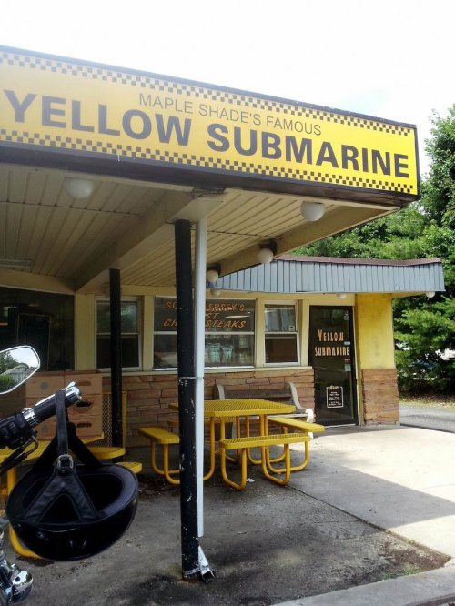 A diner named "Yellow Submarine" with outdoor seating and a sign, featuring a classic yellow and black design.
