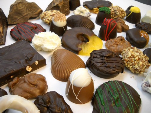 An assortment of various chocolates and confections arranged on a white surface, showcasing different shapes and toppings.