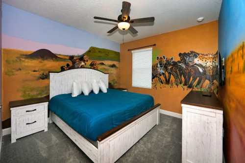 A colorful bedroom featuring a blue bedspread, wooden furniture, and vibrant animal murals on the walls.