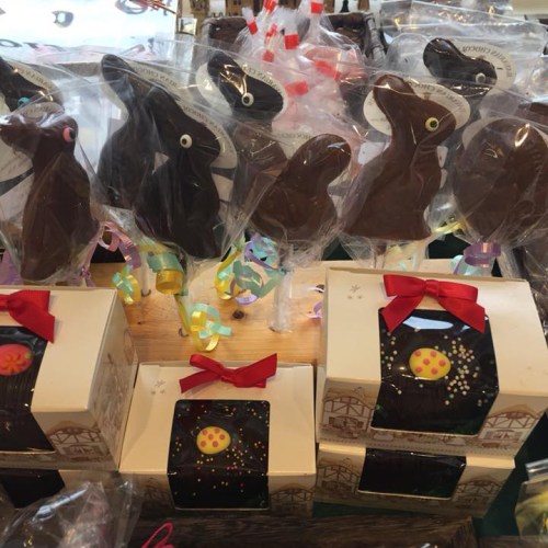 A display of chocolate bunny lollipops and decorated chocolate boxes with colorful ribbons and sprinkles.