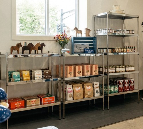 A display of shelves filled with various packaged goods, jars, and decorative items in a bright, inviting space.