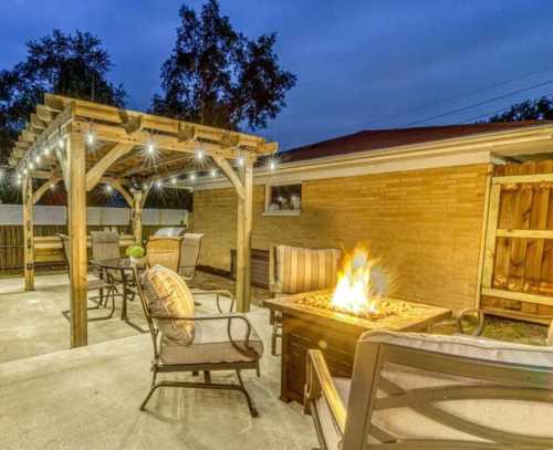 Cozy outdoor patio with a fire pit, seating area, and string lights, set against a twilight sky.