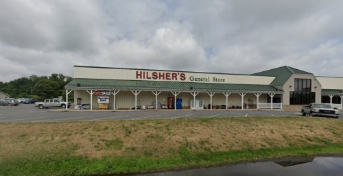 Exterior of Hilsher's General Store, featuring a green roof and various outdoor displays, set against a cloudy sky.