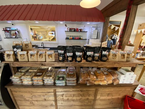 A wooden display shelf filled with various baked goods, including cookies, bread, and packaged treats.
