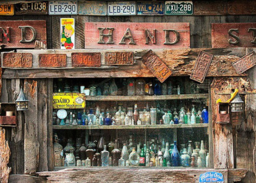 A rustic wooden display featuring various vintage bottles and old license plates.