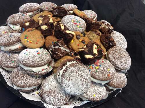 A platter of assorted cookies and brownies, including whoopie pies, chocolate chip, and sprinkled treats.