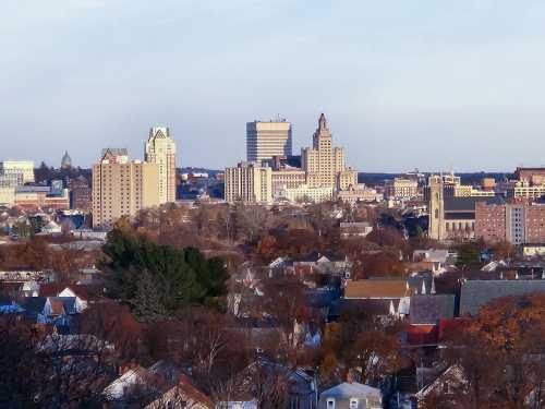 A city skyline featuring tall buildings and a mix of residential areas under a clear sky.