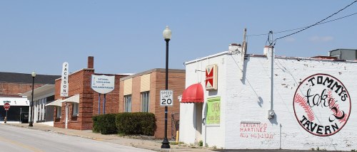 Street view featuring buildings, a tavern with a mural, and signage for Jackson, with a speed limit sign.