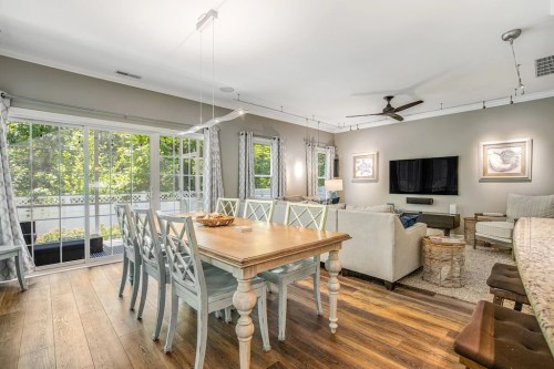Bright, modern living space with a dining table, comfortable seating, and large windows overlooking greenery.